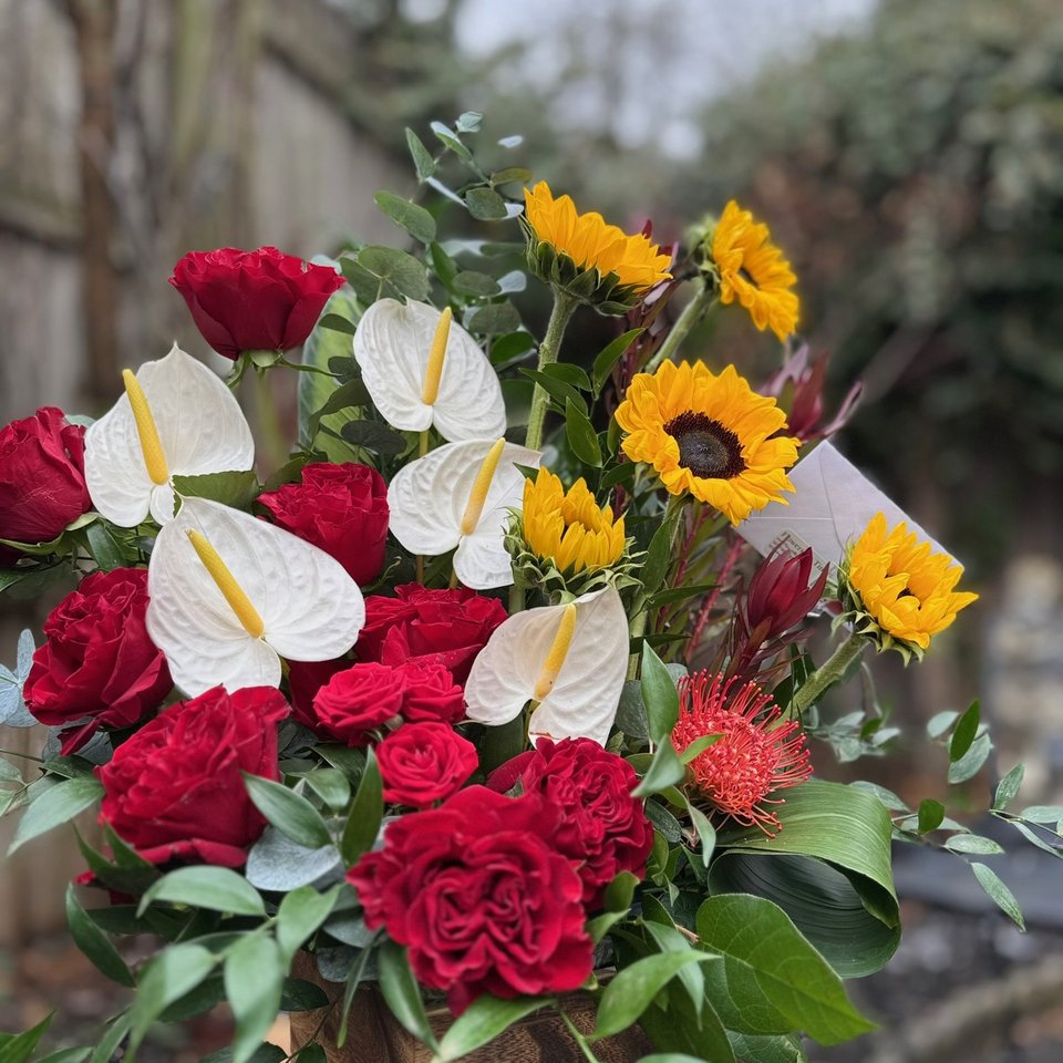 Red roses, white anthurium, and sunflowers