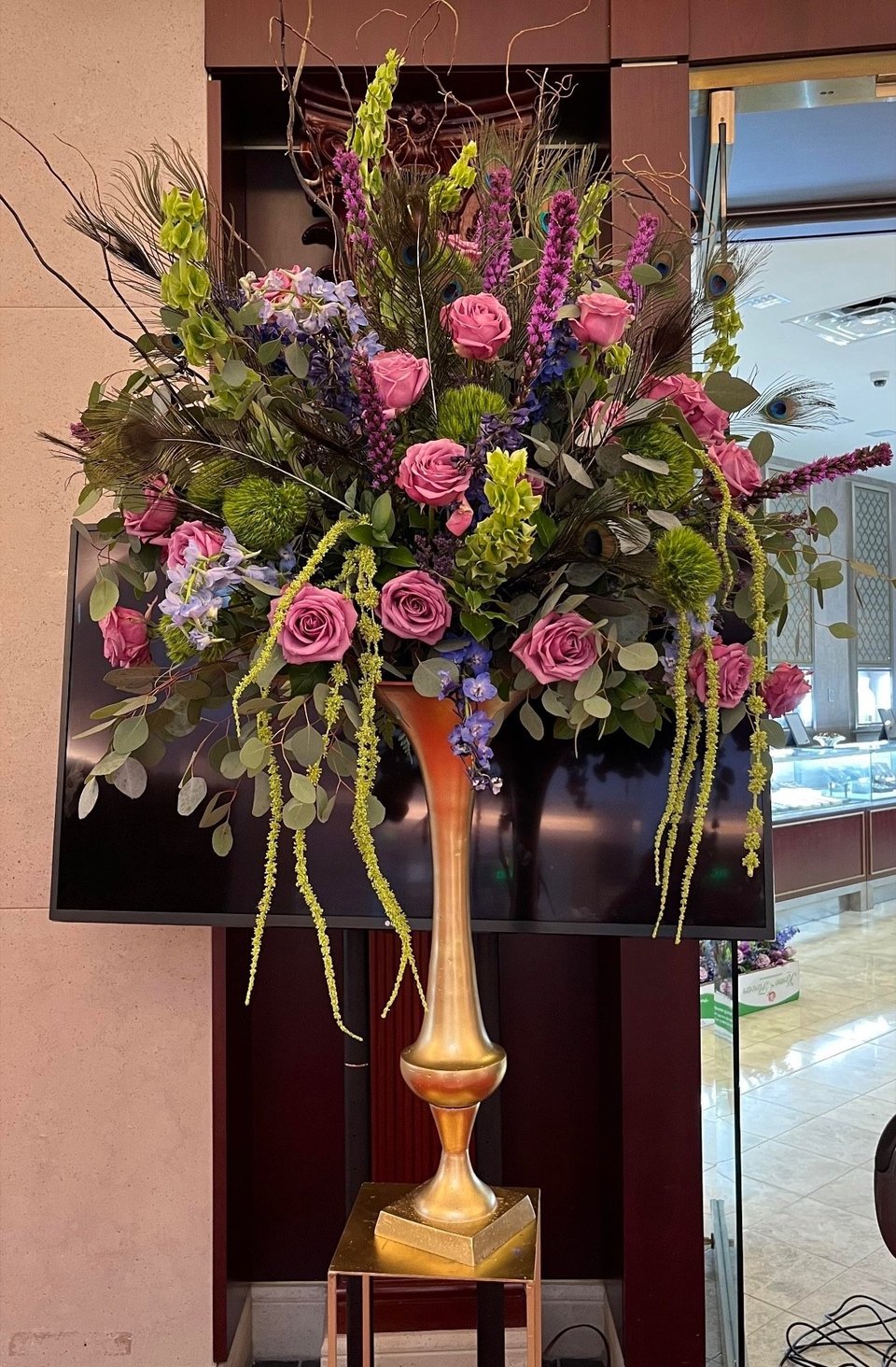 Tall pink and purple arrangement in a gold vase