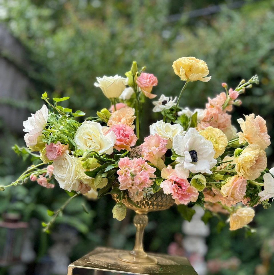 Peach, pink, and white garden arrangement in a gold compote