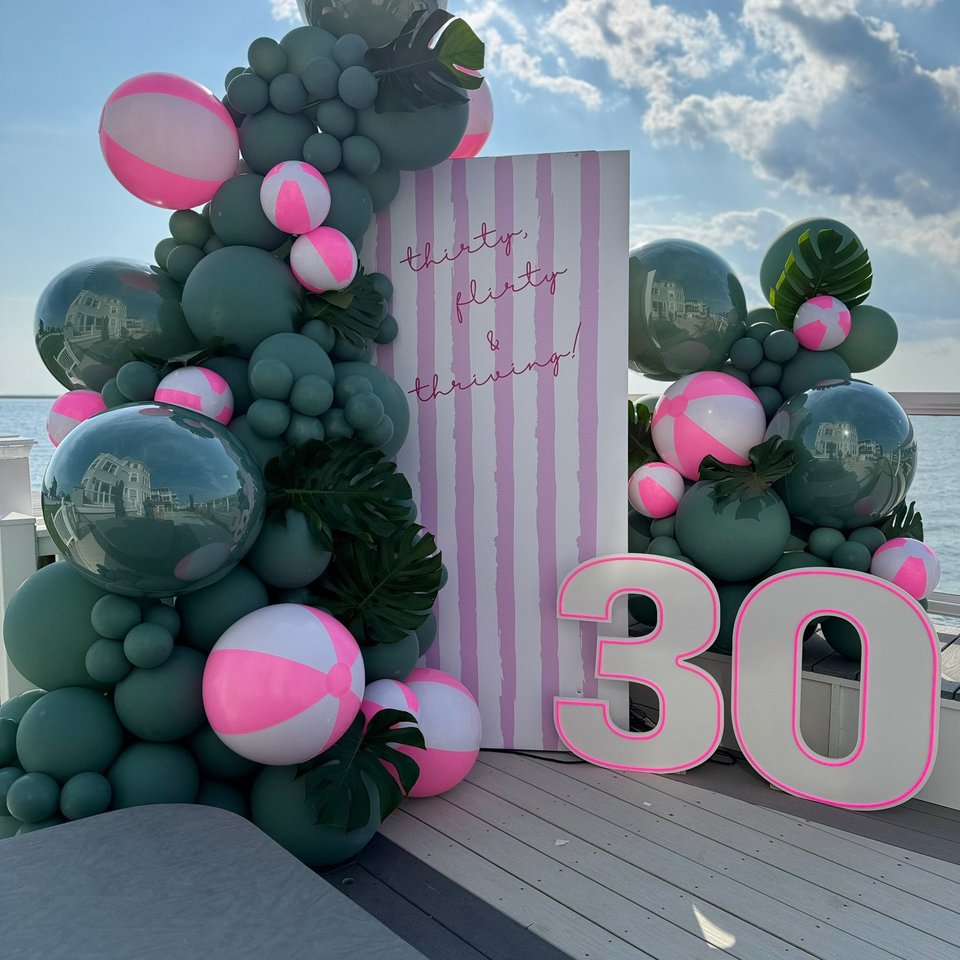30th birthday backdrop with green and pink balloons by the water