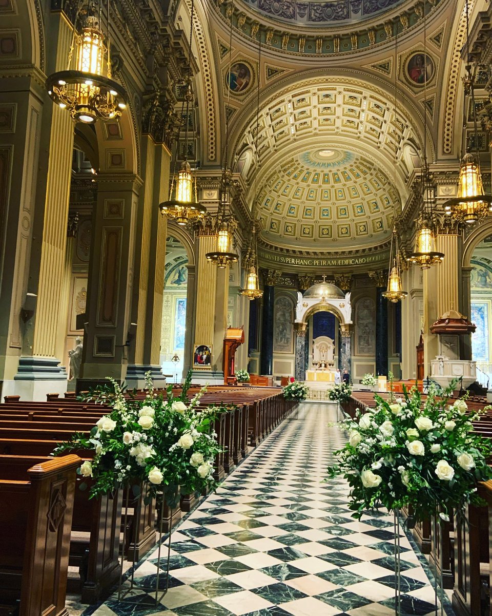Cathedral aisle lined with white arrangements