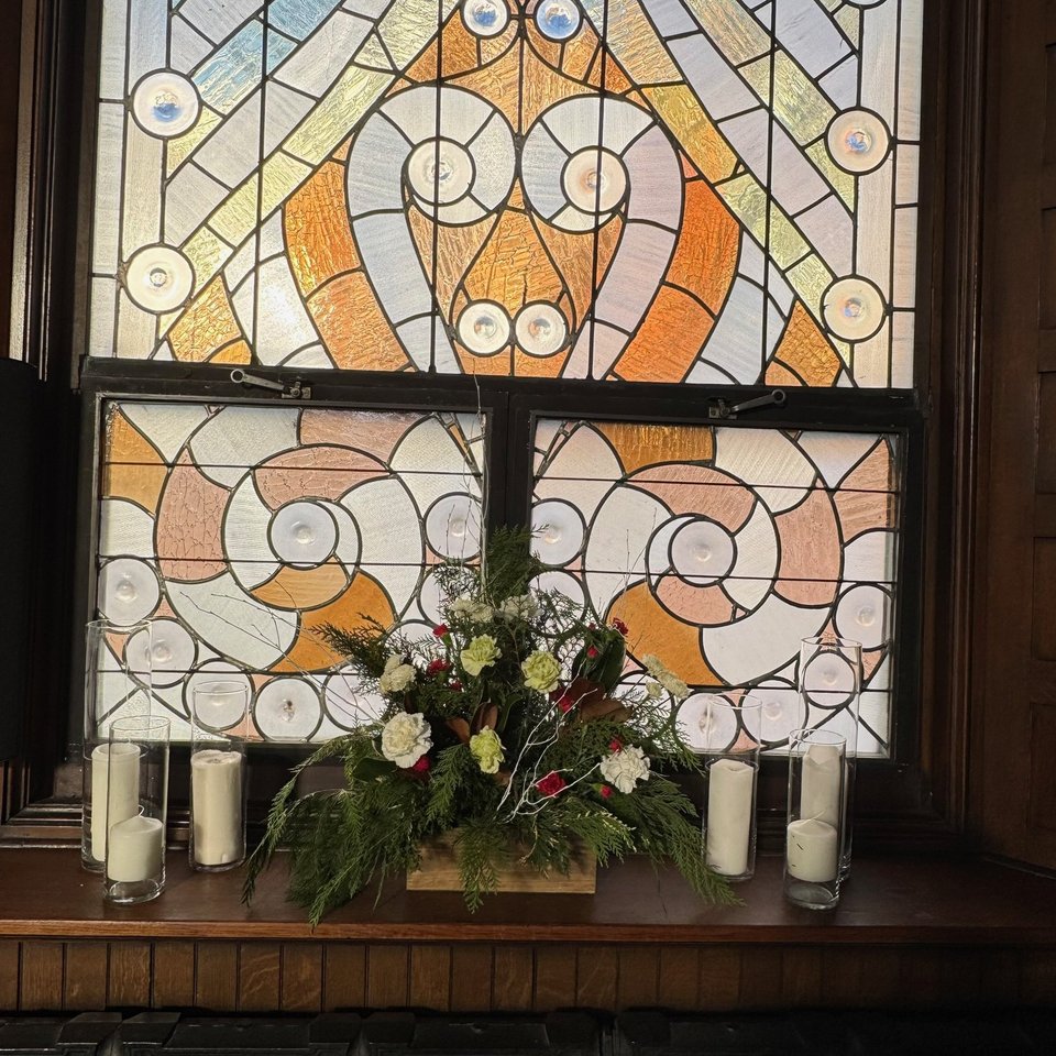 Altar flowers beneath a stained glass window