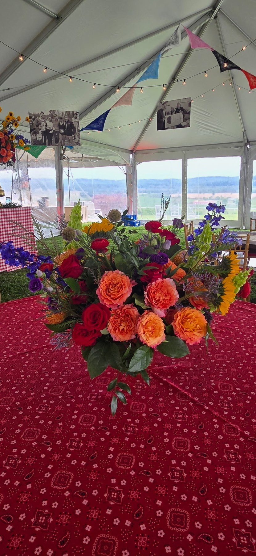 Orange and purple arrangement on a red tablecloth in a tent