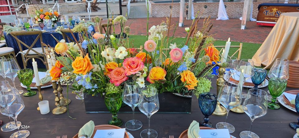 Low runner of orange and peach flowers on a dining table