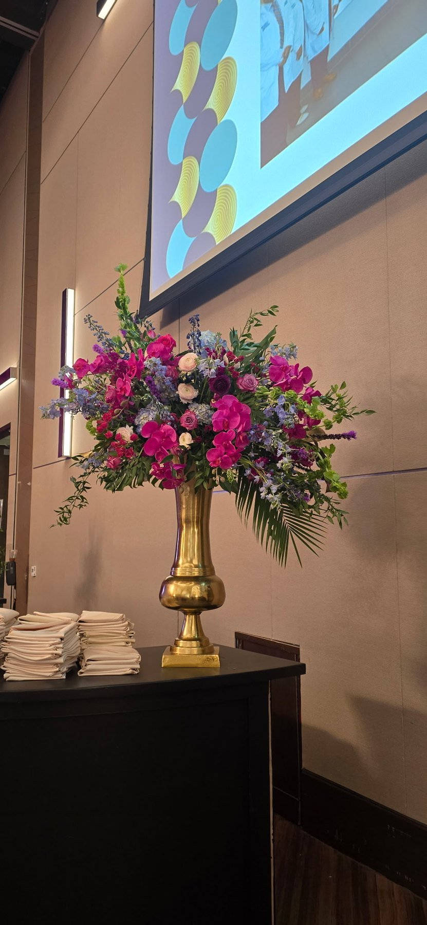 Pink and purple arrangement in a tall gold vase