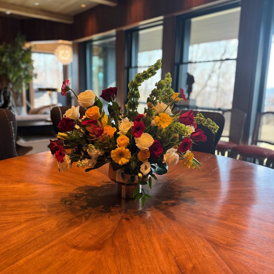 Orange, yellow, and red arrangement on a round wood table