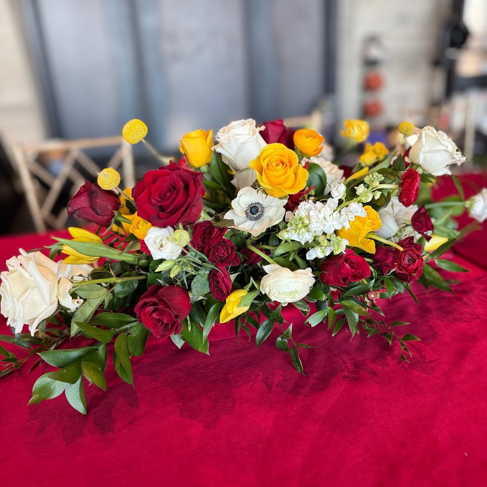 Red, white, and yellow rose centerpiece on a red tablecloth