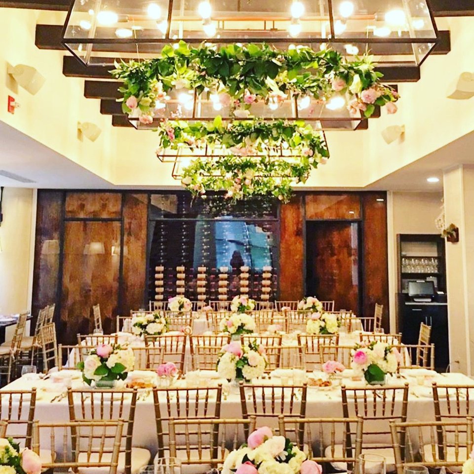 Reception hall with greenery chandeliers above long tables