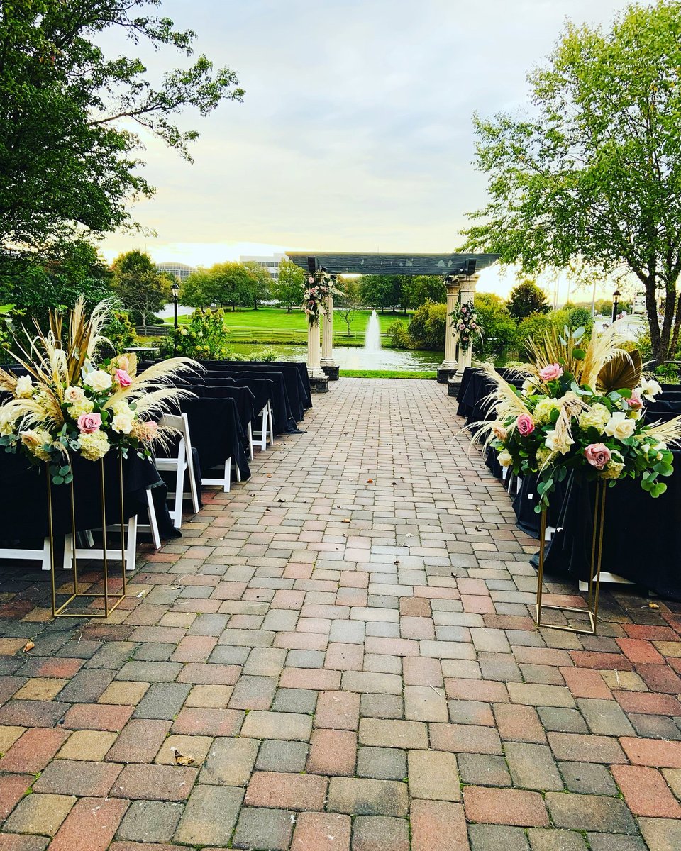 Brick garden aisle lined with floral arrangements