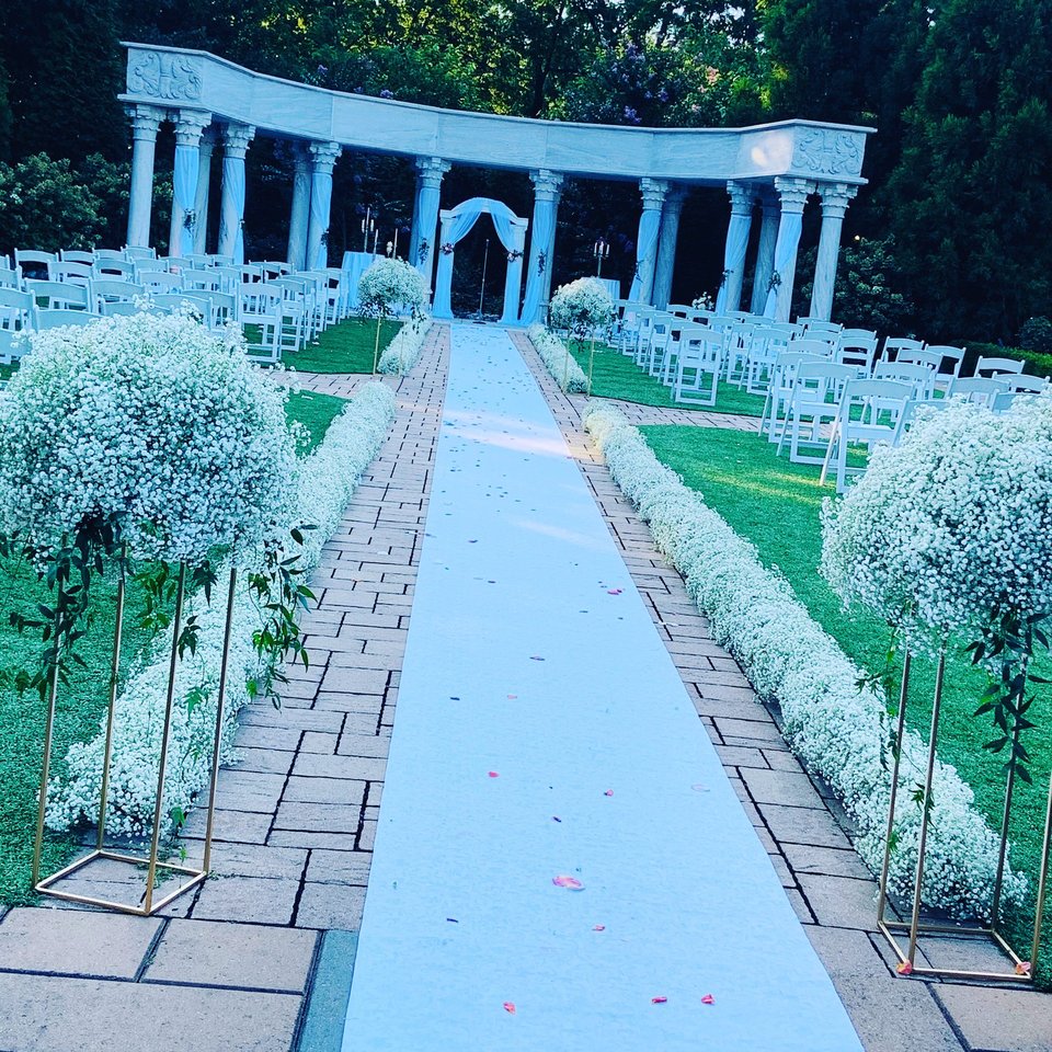 Aisle lined with baby's breath spheres and a white runner