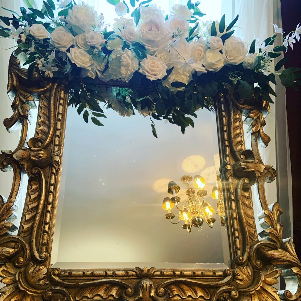 Gold mirror topped with white roses and greenery
