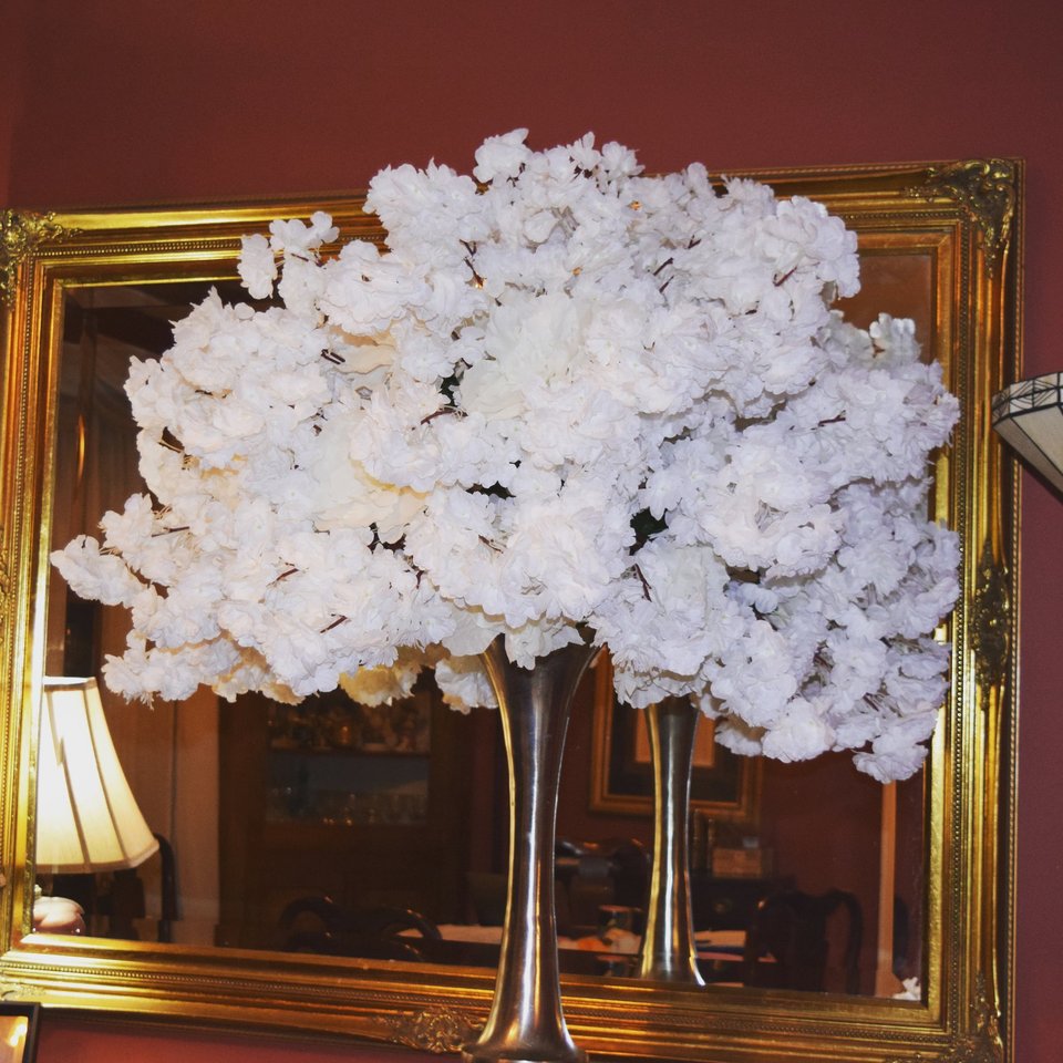 White blossom tree centerpiece in front of a gold mirror