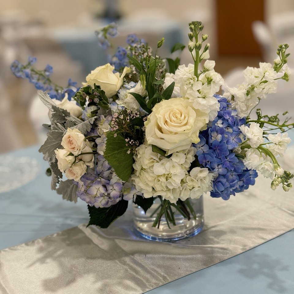 Blue and white centerpiece on a light blue runner