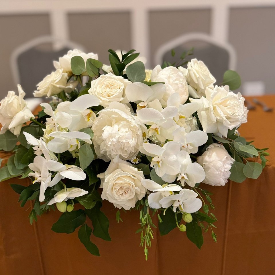 White roses and orchids in a long arrangement