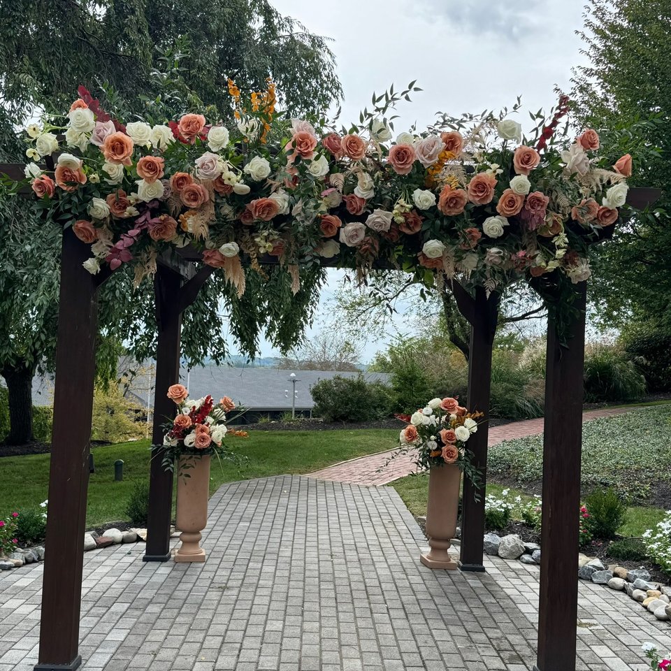Wooden pergola dressed with peach and ivory roses